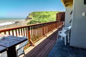 balcón con mesa y sillas y la playa en Mitford Lodge, en Morganʼs Bay