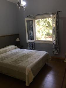 1 dormitorio con cama y ventana en CASA - CHALET VILLA DEL DIQUE en Villa del Dique