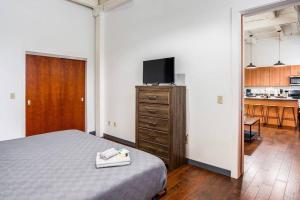 a bedroom with a bed and a dresser with a television at Centric NY Style Loft w/King bed in Rochester
