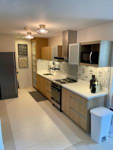 uma cozinha com electrodomésticos de aço inoxidável e bancadas brancas em 3BD/3BA Penthouse - Tropical Oasis in Pico de Loro em Patungan