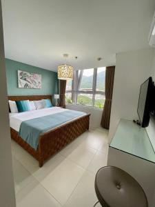 a bedroom with a bed and a desk and a television at 3BD/3BA Penthouse - Tropical Oasis in Pico de Loro in Patungan