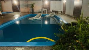 a swimming pool with two white chairs in it at Casa c piscina matinhos S Etiene in Matinhos