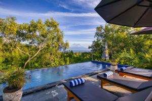 una piscina con 2 sillas y una sombrilla en Le Green Village en Nusa Penida