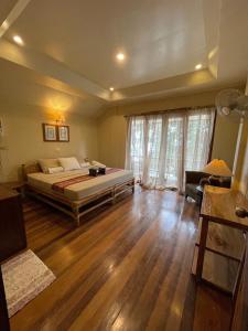 a bedroom with a large bed and a wooden floor at Casita Ysabel in Mabini