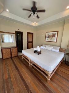 a bedroom with a large bed with a ceiling fan at Casita Ysabel in Mabini