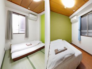 Business Hotel Taiyo في أوساكا: غرفة نوم بجدران خضراء وسرير بعمود