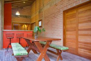una mesa de madera y un banco en una habitación con una pared de ladrillo en Casa com quintal arborizado e lazer em Trancoso, en Porto Seguro