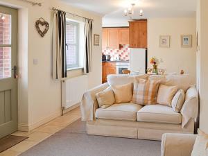 uma sala de estar com um sofá e uma cozinha em Lily Broad Cottage em Burgh Saint Margaret