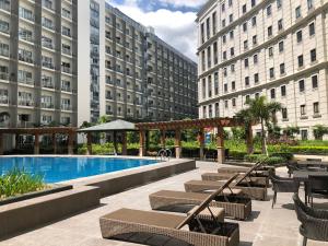 een hotelzwembad met stoelen, tafels en gebouwen bij Robles’ Unit at 81 Newport Boulevard in Manilla