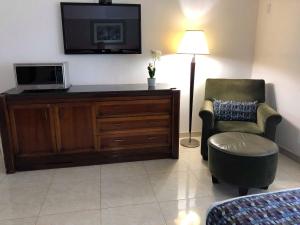 a living room with a tv and a chair at Zona Dorada Suites in Mazatlán