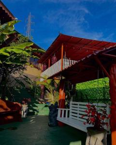 une maison avec une terrasse couverte et un banc blanc dans l'établissement Dreams Lodge Orosi, à Cartago