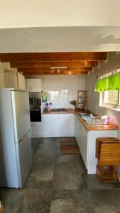 cocina con armarios blancos y nevera blanca en Casa Linda vista en Curanipe