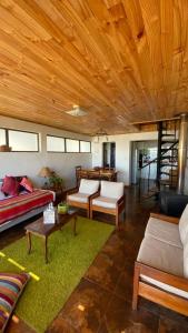 una sala de estar con sofás y techo de madera. en Casa Linda vista en Curanipe