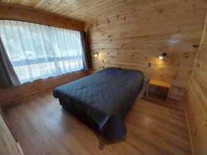 1 dormitorio con 1 cama en una cabaña de madera en Cabaña Las Aguilas, en Boca Pupuya