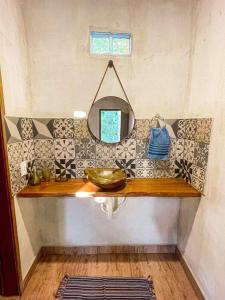 a bathroom counter with a mirror and a sink at Pousada Flor de Laranjeira in Goiás