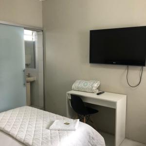 HOTEL LIFE IJUI في ليجوي: غرفة نوم مع سرير ومكتب مع تلفزيون على الحائط