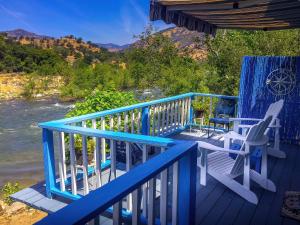 um deque azul com cadeiras e vista para um rio em Rio Sierra Riverhouse em Three Rivers