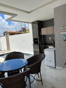 a patio with a table and chairs and a kitchen at Casa da Praia Carapibus in Conde