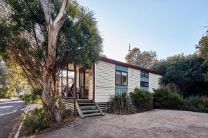 une petite maison avec une véranda et un arbre dans l'établissement NRMA Bathurst Panorama Holiday Park, à Bathurst