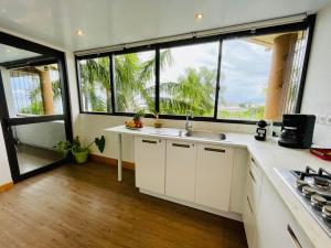 a kitchen with a sink and a large window at Tunui City Apartment - Quiet & Pool in Papeete