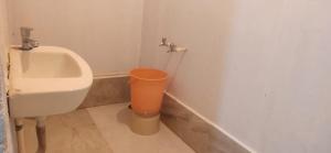 a bathroom with a urinal and an orange trash can at Hilltone panorama bungalow veg non veg matheran in Matheran