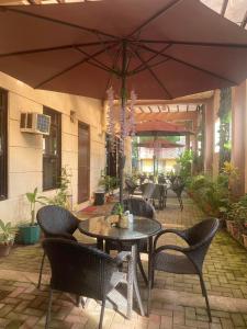 eine Terrasse mit einem Tisch, Stühlen und einem Sonnenschirm in der Unterkunft Coron Visitors Hotel in Coron