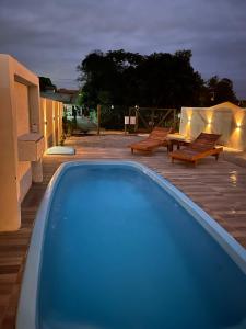 una piscina por la noche con sillas y mesas en Casa charme da lagoa, en Imbituba
