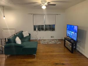 ein Wohnzimmer mit einem grünen Sofa und einem Flachbild-TV in der Unterkunft Cozy Large home, 19 Min from Hartsfield-Jackson international- Domestic Airport! in Conley