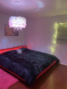 um quarto com uma cama preta e um lustre em Cozy Large home, 19 Min from Hartsfield-Jackson international- Domestic Airport! em Conley