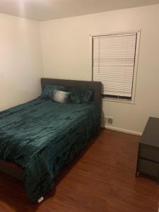 ein Schlafzimmer mit einem Bett mit einer grünen Decke und einem Fenster in der Unterkunft Cozy Large home, 19 Min from Hartsfield-Jackson international- Domestic Airport! in Conley