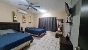 1 dormitorio con 2 camas y ventilador de techo en Casa a pie de playa isla de la piedra en Mazatlán