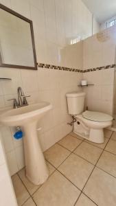 a white bathroom with a sink and a toilet at Casa a pie de playa isla de la piedra in Mazatlán