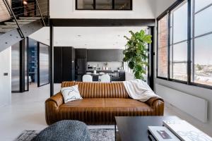 a living room with a brown couch and a kitchen at New York Converted Warehouse Apartment in Richmond in Melbourne