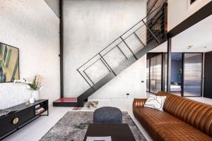 a living room with a brown couch and a staircase at New York Converted Warehouse Apartment in Richmond in Melbourne