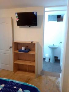 a room with a tv on the wall and a bathroom at Hospedaje Kaihalulu in Punta Hermosa