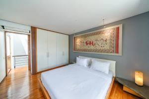 a bedroom with a white bed with a painting on the wall at Villa Rio - Contemporary 2BR Villa in Downtown Seminyak in Seminyak