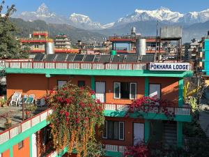 a building with flowers on it with mountains in the background at New Pokhara Lodge - Lakeside, Pokhara Nepal in Pokhara
