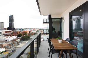The East End Apartments by Urban Rest في أديلايد: شرفة مع طاولة وكراسي خشبية