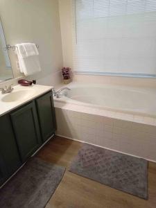 a bathroom with a bath tub and a sink at Elegant 4 bedroom house with community pool & deck in Germantown