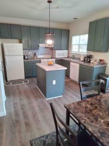 a large kitchen with green cabinets and wooden floors at Elegant 4 bedroom house with community pool & deck in Germantown