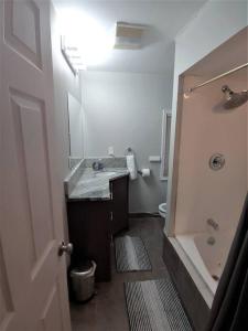 a bathroom with a sink and a tub and a toilet at 2BR Lake House 40ft Dock Access in Keego Harbor