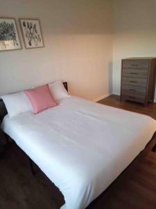 - un grand lit blanc avec un oreiller rose dans l'établissement Elegant 4 bedroom house with community pool & deck, à Germantown