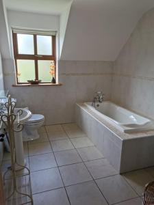 baño blanco con bañera y aseo en Comfortably Crolly Holiday Home, en Letterkenny