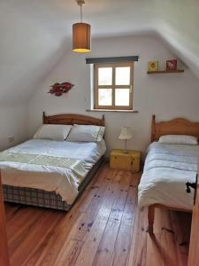 two beds in a bedroom with wooden floors and a window at Comfortably Crolly Holiday Home in Letterkenny