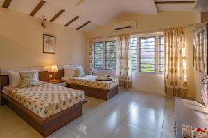 a bedroom with two beds and a window at StayVista at Anjali with Free Breakfast & Terrace Access in Kozhikode