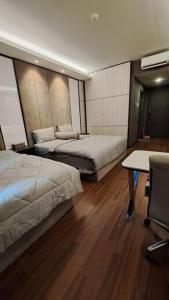 a bedroom with two beds and a table and a desk at Aston Apartment Batam Floor 21 in Nagoya