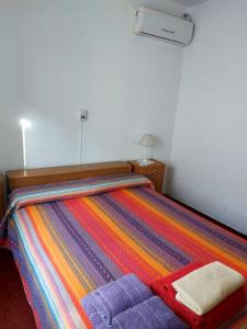 Una cama con una manta de colores encima. en Castillo Del Lago - Carlos Paz - D17 en Villa Carlos Paz