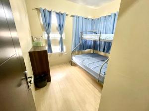 アンヘレスにあるMago Nouveau Residence 3bdrm-3bath Subdivisionの青いカーテン付きの二段ベッドが備わる小さな客室です。
