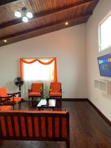 MY HOUSE IN MACAS, MIRADOR AL UPANO في Macas: غرفة معيشة مع كراسي برتقالية وتلفزيون بشاشة مسطحة