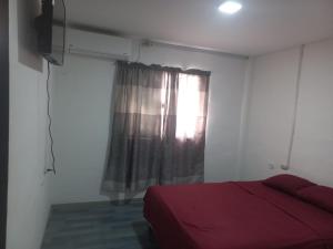 Un dormitorio con una cama roja y una ventana. en Habitación Suites Playas, en Playas
